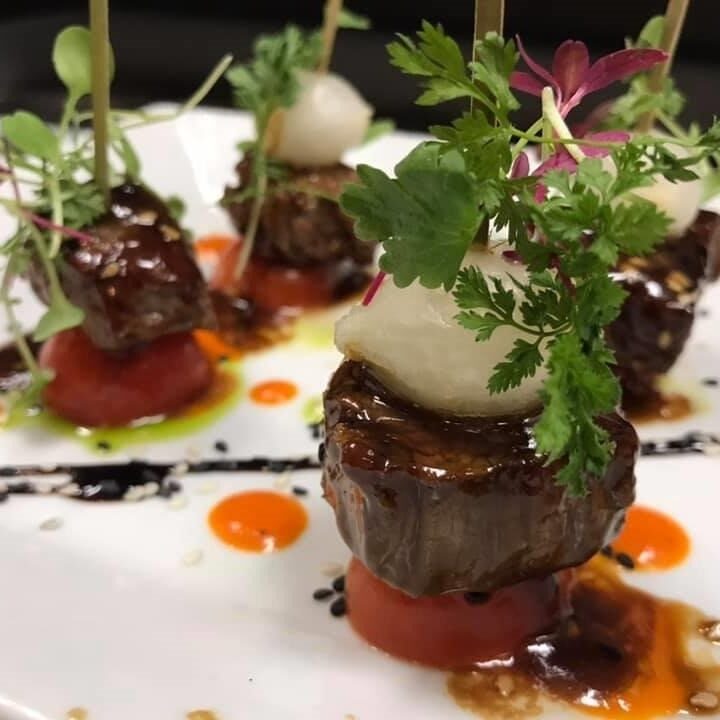 Gourmet steak medallions topped with greens and sauce.