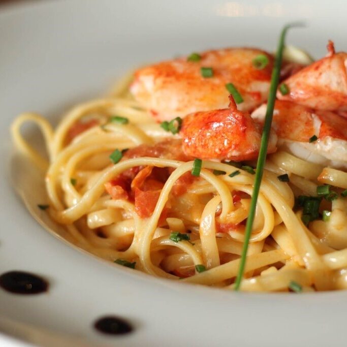 Shrimp pasta garnished with herbs on a white plate. Shrimp pasta garnished with herbs on a white plate.